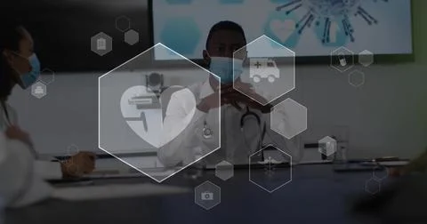 Lead Dr gesturing during medical meeting after slide to review case, hex icons 库存照片