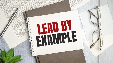 Lead by example text on notepad with glasses, pen and charts Stock Photos
