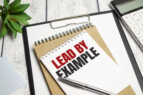 Lead by example, text on white paper on the light background with charts pape Stock Photos