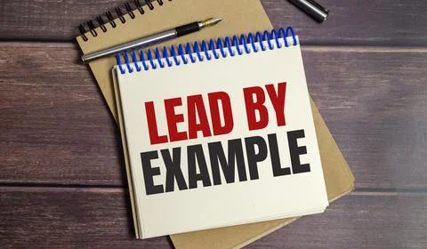 Lead by example words on notepad and wooden background Stock Photos