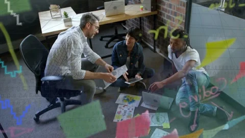 Lead holding mockup, team refining layout, reviewing designs on tablet, overlays Stock Footage 333278028
