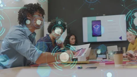 Lead presenter leaning forward referencing mockup at table, HUD guiding Stock Footage 333169675