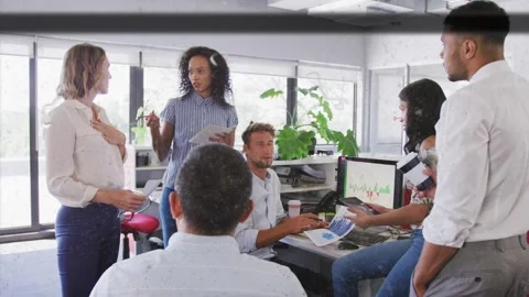 Lead presenting meeting, team exchanging charts and pointing at graph for Stock Footage 333936619