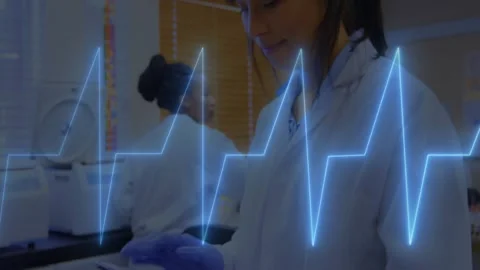 Lead tech tapping tablet as camera moving closer, ECG overlay pulsing and Stock Footage 331613932