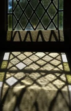 Leaded Glass Window Casting Patterned Sunlight Shadow on Stone Sill Stock Photos