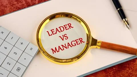 Leader vs manager is shown through a magnifying glass in red letters in a not Stock Photos