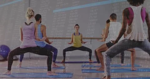 Leading trainer guiding squat in studio in yellow-tank dark-leggings with blue 写真素材
