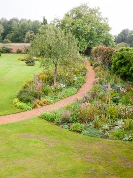 Leading walking path through garden in summer overcast scene Stock Photos