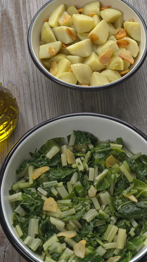 Leaf beet and boiled potatoes with fried garlic in bowls.  Vertical video. Video stock 281174124