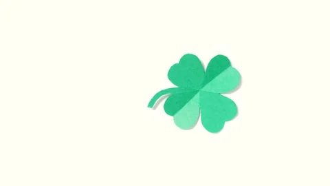 A leaf of clover cut out of paper is spinning on a shiny green background. Stock Footage 169635851