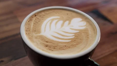 A leaf design is seen in the foam of a cup of coffee Stock Footage 253408071