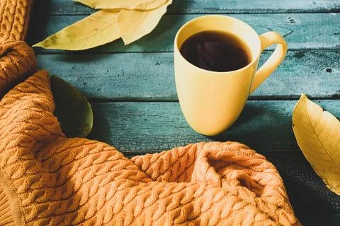 Leaf fall mood, yellow cup of coffee with a knitted scarf and fallen leaves.. Stock Photos