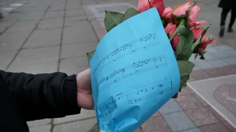 Leaf with notes of blue color with a bouquet of roses in the hands of a young Stock Footage 226313784