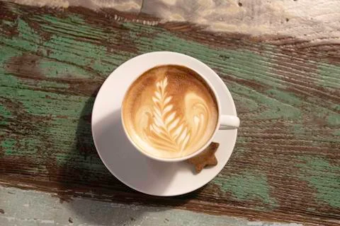 Leaf shape  on a coffee cup over a wooden table Stock Photos