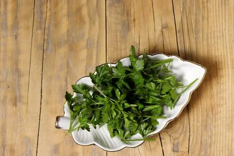 Leaf-shaped ceramic dish filled with fresh parsley. Stock Photos