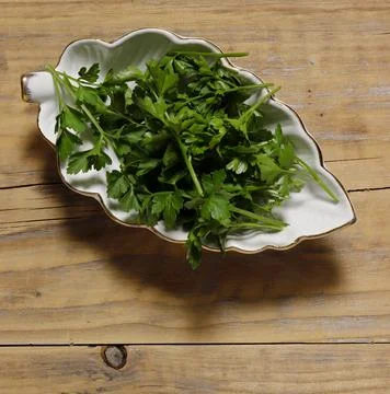 Leaf-shaped ceramic dish filled with fresh parsley. Stock Photos