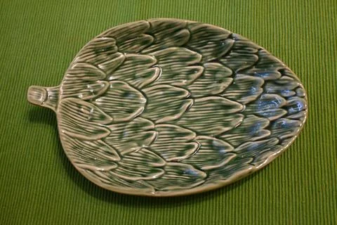 Leaf-shaped ceramic plate on green textile Photos