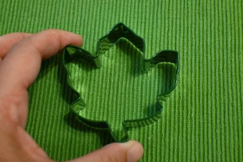 Leaf-shaped cookie cutter on green textured surface 스톡 사진