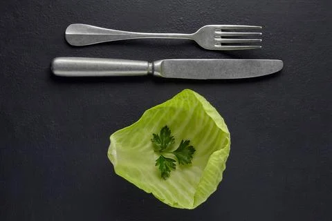 A leaf of white cabbage with a leaf of parsley and a fork with a knife on a Stock Photos
