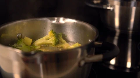 Leafy greens being added to a pot of broccoli Stock Footage 105863349