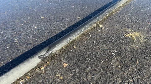 Leaking black polyethylene water pipe on ground outdoors Stock Footage 276890657