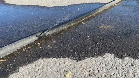 Leaking black polyethylene water pipe on ground outdoors Stock-Footage 276890660
