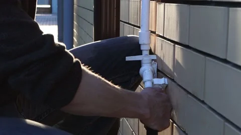 Leaking water pipe and splashing water in the house. A man repairs a crane . Stock Footage 154408284