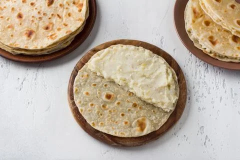 Lean flatbread stuffed with potatoes on a wooden board, light gray background Stock Photos