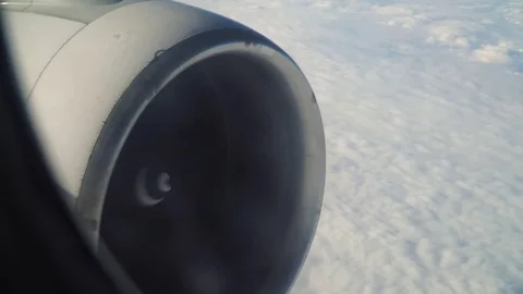 Leaning aircraft passenger window view of airplane turbine above clouds Video stock 84510656