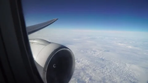 Leaning aircraft passenger window view of airplane turbine above clouds. Stock Footage 84742559