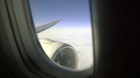 Leaning aircraft passenger window view of airplane turbine above clouds. Stock Footage 84774534