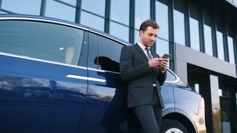 Leaning on the automobile, using smartphone Stock Footage 243640608