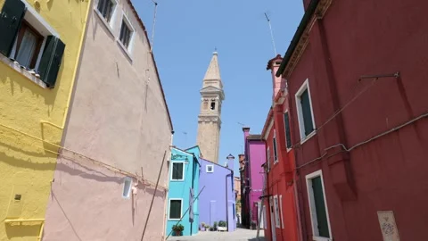 Leaning campanile (bell tower) rises behind colorful buildings in Burano Stock Footage 338265182