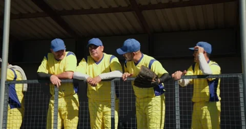 Leaning, diverse senior baseball teammates wiping sweat and shielding eyes on Stock Footage 344946172