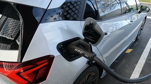 Leaning into fast charger handle that is plugged into an electric car charging Stock Footage 171615530