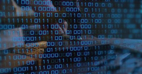 Leaning female analyst coding on laptop at dim desk, wearing dark top, glasses Stock-Fotos