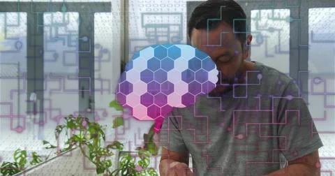 Leaning man in gray shirt using device at office, with hexagonal brain overlay, 库存照片