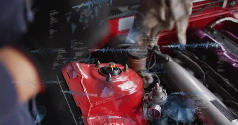Leaning mechanic in dark jacket inspecting garage engine bay, touching red strut 스톡 사진