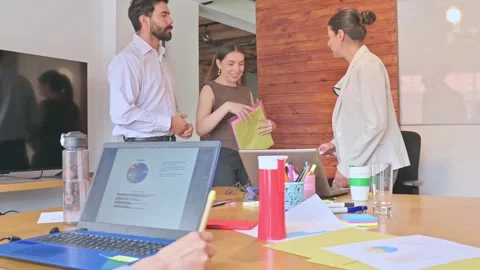Leaning over paperwork to review documents together in a bright office. 動画素材 336569928
