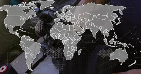 Leaning tech in dark jacket, soldering cables at bench with white world map Stock Photos