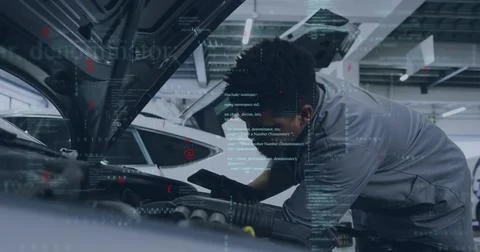 Leaning tech in gray coverall gloves, checking engine with phone under open hood Stock Photos