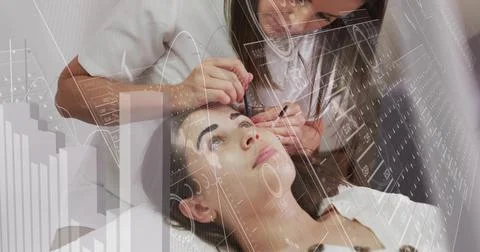 Leaning tech shaping eyebrows on reclining client in spa bed, holding tool white Stock Photos