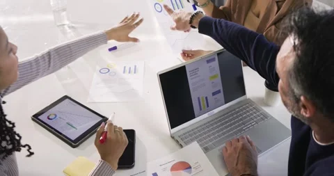 Leaning in, three colleagues are examining charts around table and jotting notes Stock Footage 336897153