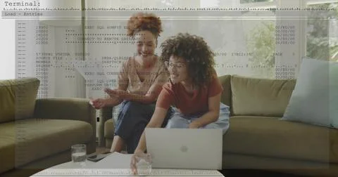 Leaning women checking code on silver laptop at home, wearing short sleeves, Foto stock