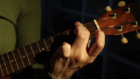 Learn basic guitar chords and strumming techniques in a cozy indoor Stock Footage 303934442