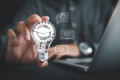 Learn e learning via technology, hand holds lightbulb filled with gears and.. Stock Photos