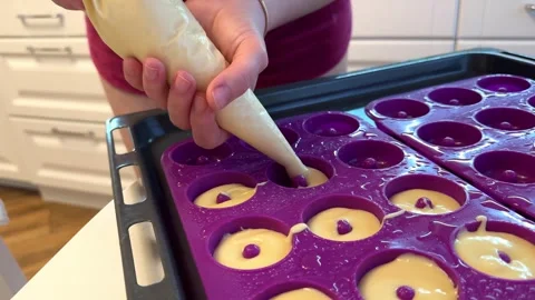 Learn to make donuts by filling molds with batter in a kitchen at home 스톡 동영상 331901669