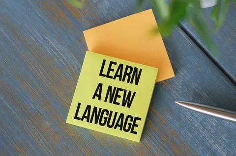 Learn a new language text on note pad with pen, wooden background. Stock Photos