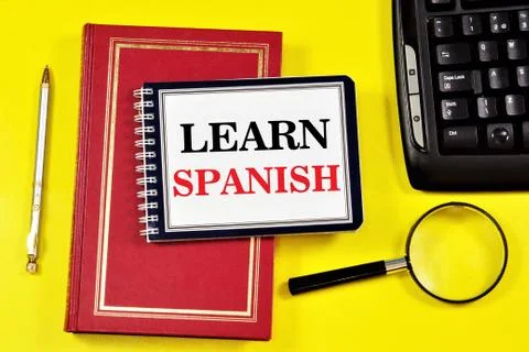 Learn Spanish.- writing text in a notebook on a textbook. Stock Photos