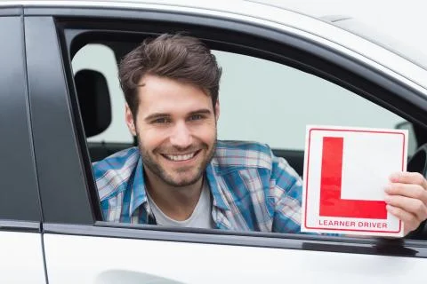 Learner driver smiling and holding l plate Stock Photos